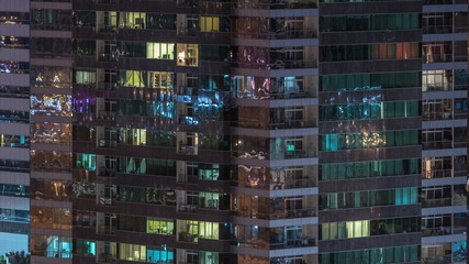 Windows of the multi-storey building of glass and steel lighting inside and moving people within timelapse