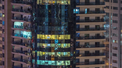 Fototapeta na wymiar Windows of the multi-storey building of glass and steel lighting inside and moving people within timelapse