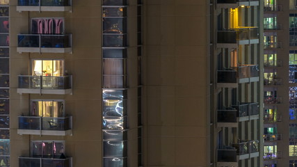 Obraz premium Windows of the multi-storey building of glass and steel lighting inside and moving people within timelapse