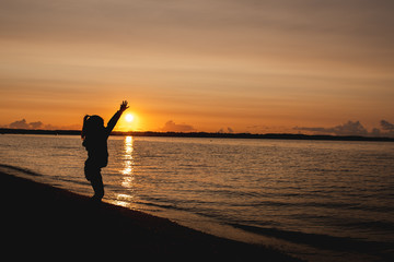Fototapeta premium silhouette of a child on the background of the setting sun on the beach