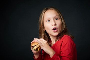 Closeup of a girl holding going to eat a burger looking back over shoulder with a look of surprise