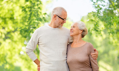 Obraz premium old age and people concept - happy senior couple hugging over green natural background