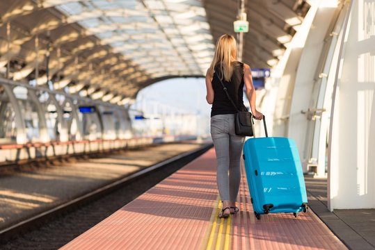 Woman with blue baggage suitcase walking on train station