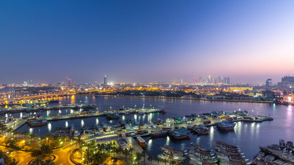 Obraz premium Dubai creek landscape day to night timelapse with boats and ship near waterfront