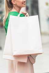 cropped shot of smiling young woman holding shopping bags
