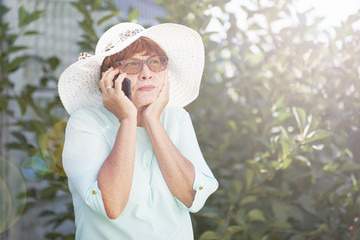 aged woman talking on phone. old lady in Park. Sunny day, happy mood. upset senior woman with phone