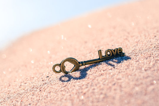 Schl&uuml;ssel mit einem Herz und dem Wort Love im Sand Symbol f&uuml;r Liebe