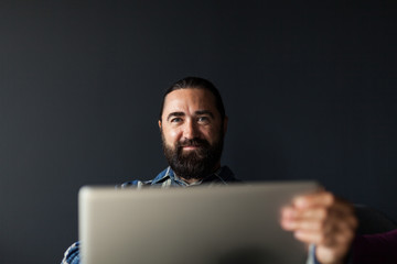 Portrait of smiles adult handsome businessman with laptop.