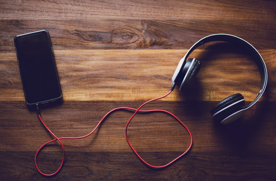 Object technology,Digital smartphone and white headset on wooden background