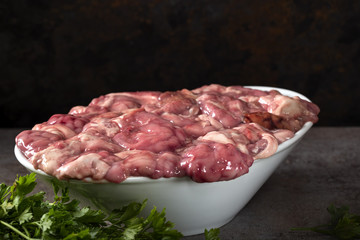 Raw pork brain in bowl with some green fresh parsley