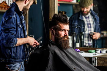 Barber with clipper styling hair of brutal bearded client. Hipster client getting haircut. Hipster...