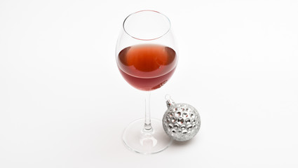 Christmas menu concept. Wineglass with red liquid or wine and christmas ball ornament isolated on white background. Winter celebration with alcohol drink. Glass with wine and christmas decoration