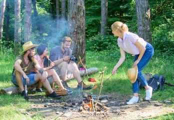Naklejka na ściany i meble Summer picnic. Tourists hikers sit on log relaxing waiting picnic snack. Picnic with friends in forest near bonfire. Hikers relaxing during snack time. Company having hike picnic nature background