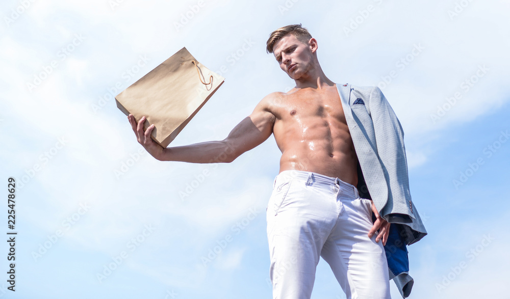 Wall mural Sales season. Shop assistant concept. Man muscular athlete hold shopping bag sky background. Hot sales and discount. Guy attractive macho carry shopping bag made out of brown paper. Eco package