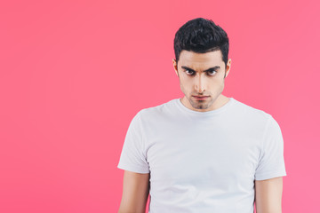 Fototapeta premium handsome serious man looking at camera isolated on pink