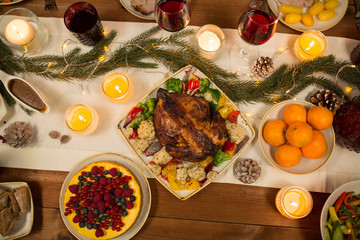 Fototapeta na wymiar christmas dinner and eating concept - roast chicken or turkey and other food on table