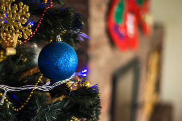 artificial Christmas tree beautifully decorated with balloons, toys and garlands, flashing lights, close, selective focus, blurred fireplace in the background