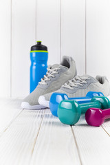 Sneakers, water and dumbbell on wooden wall background as a sport and fitness symbols