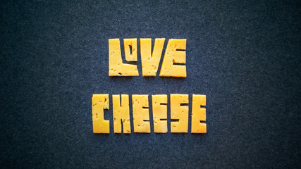 Love Cheese text word on dark background. Carve yellow cheddar into letters banner. Cheese...