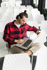 Young employee typing on laptop. Study notes, online work.