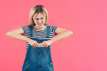 portrait of woman crushing smartphone isolated on pink