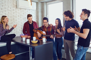 Friends playing the guitar, sing fun indoors.Happy party of friends.