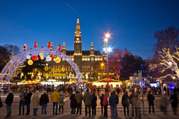 View over Rathausplatz in Vienna in Christmas time. People visiting the Christkindlmarkt and therefore waiting at the traffic lights to cross the road. Famous town hall in background.
