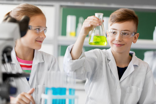 education, science and children concept - kids with test tubes studying chemistry at school laboratory