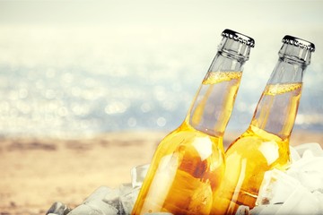 Beer bottles with ice on light background