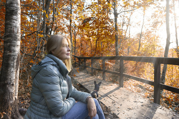 Fototapeta premium Woman walks in autumn park with little dog