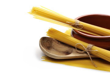 Spaghetti, yellow pasta, clay pot and wooden spoon isolated on white background 