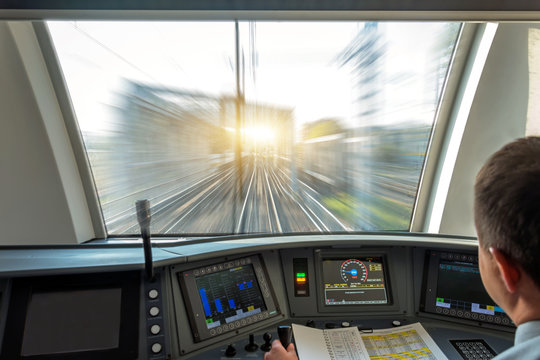 Fototapeta Train driver at the controls cab of speed passenger train, view of the railway bridge with the effect of speed motion blur.