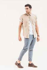 handsome stylish man in shirt posing and looking away isolated on beige