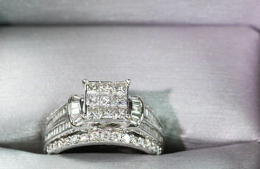 A diamond engagement ring in a box with glint/reflection. Shimmering princess-cut diamonds.