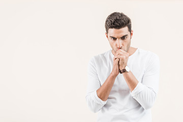 focused young man thinking and looking down isolated on beige