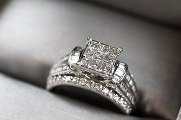 A diamond engagement ring in a box with glint/reflection. Shimmering princess-cut diamonds.