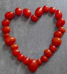 A heart of red tomatoes on a gray background