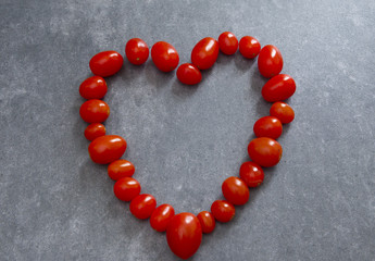 A heart of red tomatoes on a gray background
