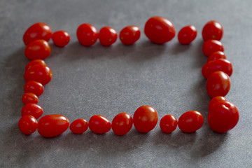 A rectangular frame of red tomatoes on a gray background