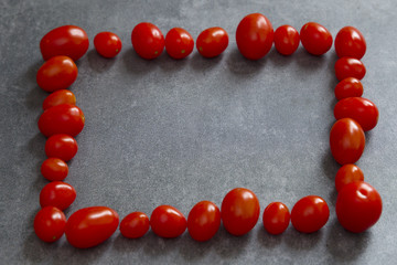 A rectangular frame of red tomatoes on a gray background