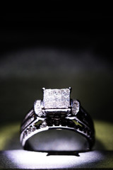 A diamond engagement ring in a box with glint/reflection. Shimmering princess-cut diamonds.