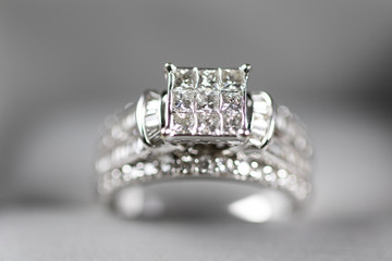 A diamond engagement ring in a box with glint/reflection. Shimmering princess-cut diamonds.