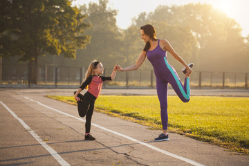 Mom and daughter on the morning sports training do a warm-up. Healthy lifestyle