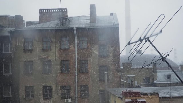Seasonal snowfall in St. Petersburg. Typical courtyard of high-rise building. View through window facade and roof covered snow.