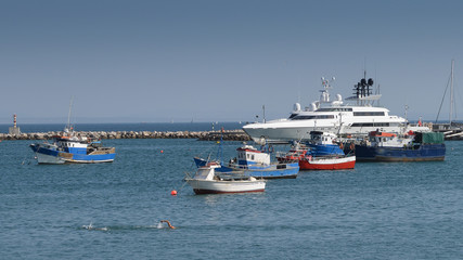 Fototapeta na wymiar Fishing boats and luxury yacht docked at Cascais marina, near Lisbon, Portugal