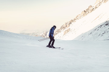 Skier skiing downhill in high mountains. The athlete is an Amateur, not a professional, cautious...