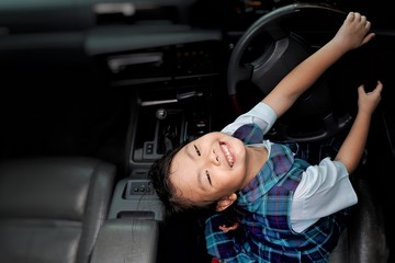 Asian little young girl smiling and sitting in the car with steering wheel.Happiness of cute kid in...