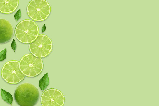 Pattern of citrus fruits.Fresh organic ripe lemon and lime with green leaves isolated on green background.Top view,flat lay with copy space empty blank for text.Food background, wallpaper.