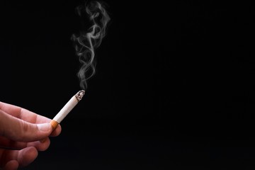 Human hand holding smoking cigarette in dark black background.Stop smoking  and Healthy care...