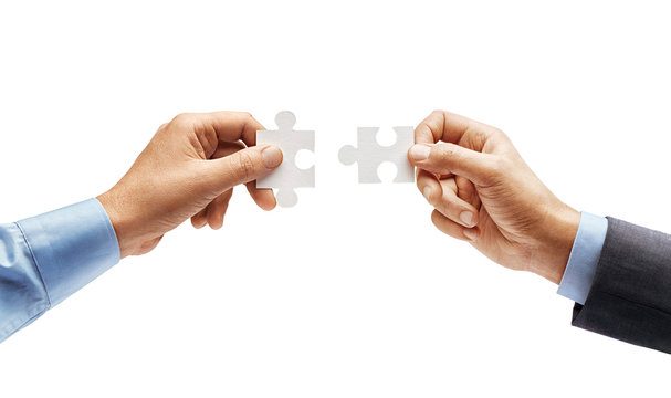 Man's hand in shirt and man's hand in suit trying to connect puzzle pieces isolated on white background. Close up. High resolution product